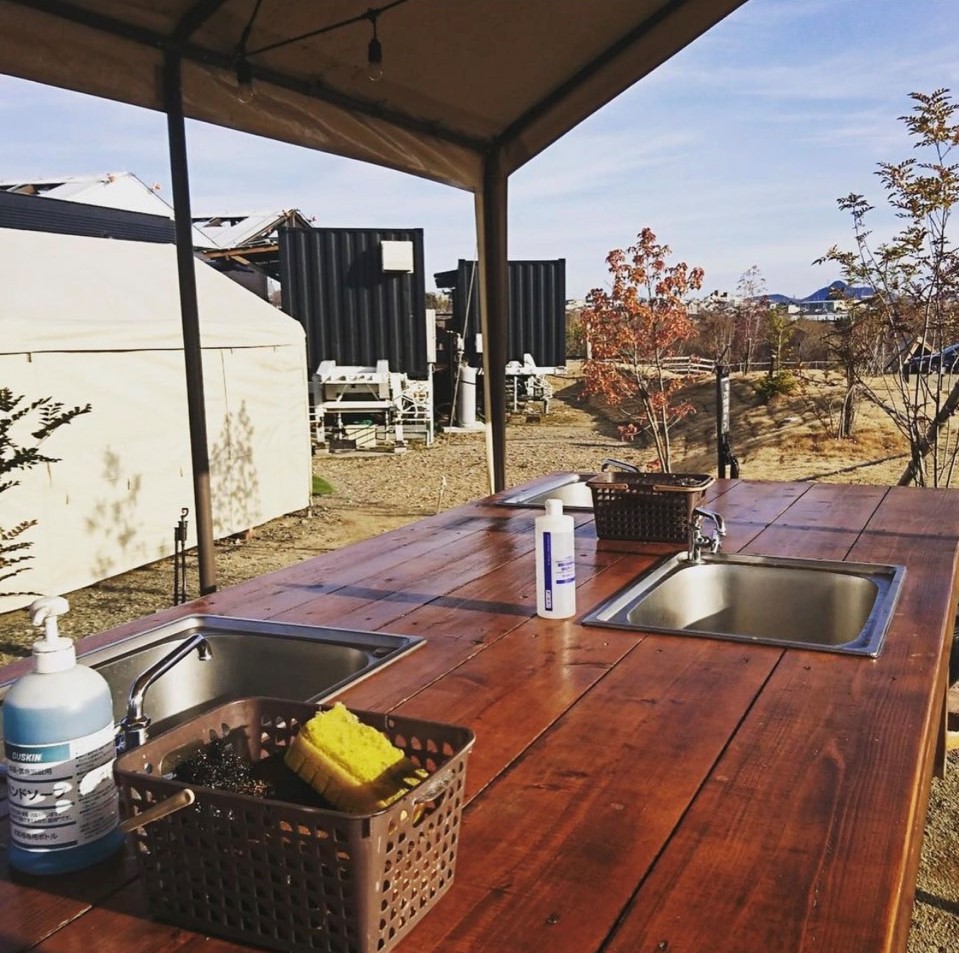 伊木山フォレスト　オートサイトの炊事場。木目調のきれいな造りでごみ置き場も備えている。